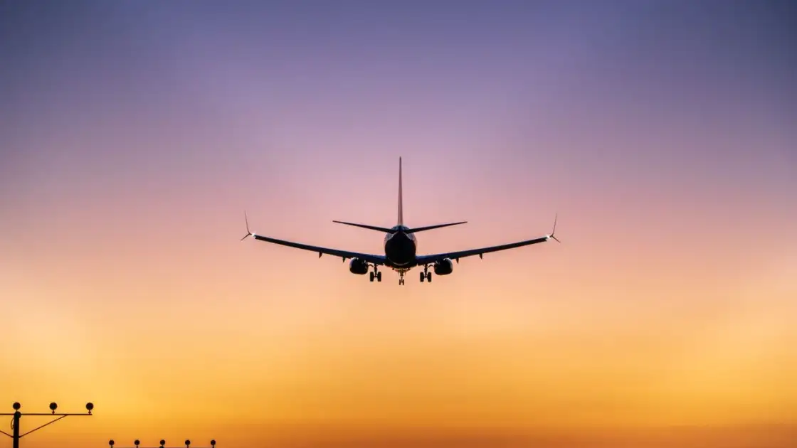 Avión comercial se aproxima a una pista de aterrizaje al atardecer