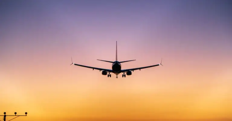 Avión comercial se aproxima a una pista de aterrizaje al atardecer