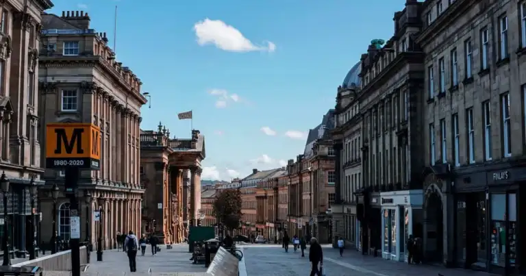 Grey Street en Newcastle upon Tyne, con edificios históricos, comercios y peatones en el centro de la ciudad