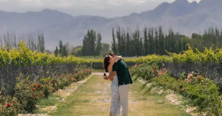 Pareja entre viñedos de Mendoza con montañas al fondo durante una visita a bodegas