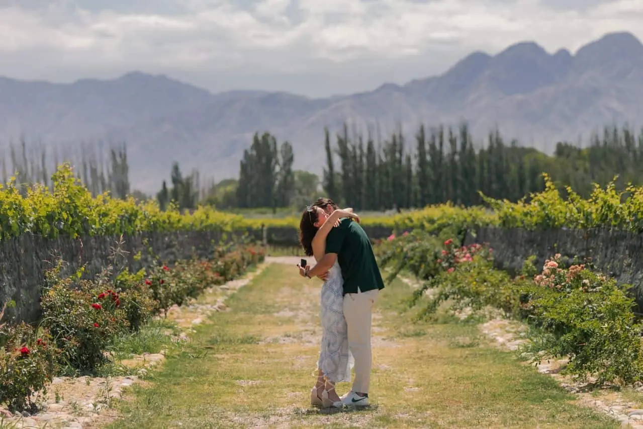 Pareja entre viñedos de Mendoza con montañas al fondo durante una visita a bodegas
