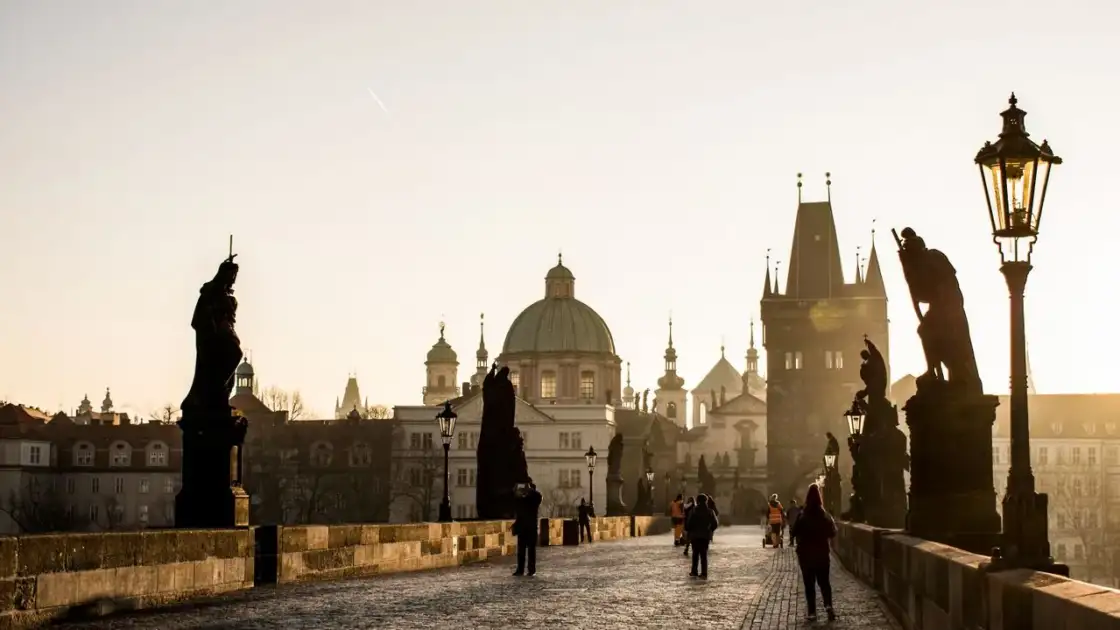 Puente de Carlos en Praga con sus estatuas y edificios históricos al amanecer
