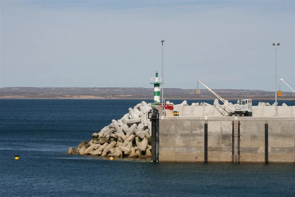 Puerto de la Patagonia con escollera, faro y paisaje costero al fondo