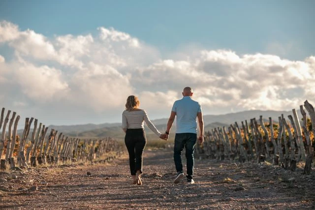 Cómo recorrer bodegas de Mendoza sin auto Pareja camina entre viñedos durante una visita a bodegas de Mendoza