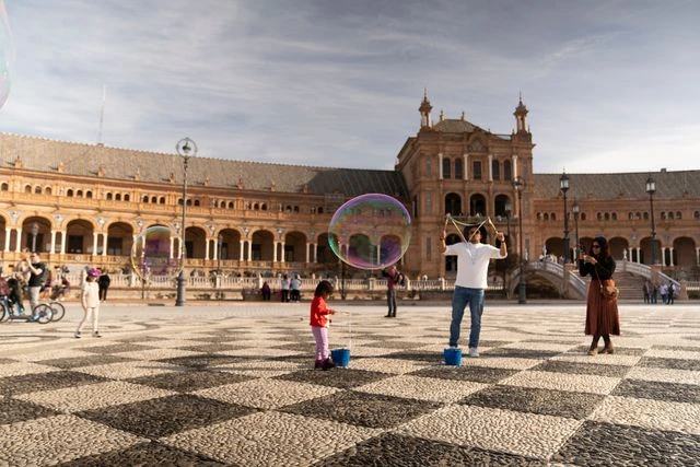 Sevilla, uno de los mejores destinos de España para viajar con niños Familias y niños disfrutan de la Plaza de España de Sevilla durante un viaje por España