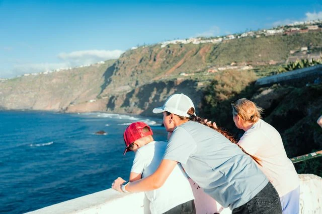 Viajar con niños a destinos de costa y naturaleza Familia contempla el mar y los acantilados desde un mirador costero durante un viaje con niños