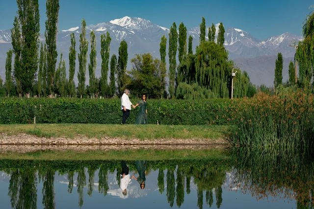 Recorrer bodegas de Mendoza sin auto entre viñedos y la Cordillera Pareja recorre un viñedo de Mendoza con la Cordillera de los Andes al fondo