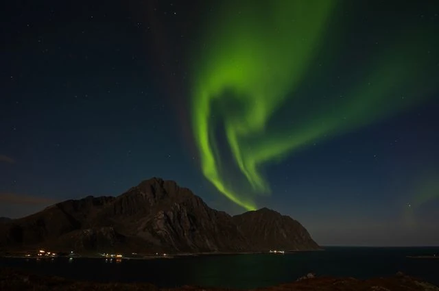 Auroras boreales: condiciones ideales para poder verlas Aurora boreal verde sobre montañas y costa durante una noche despejada