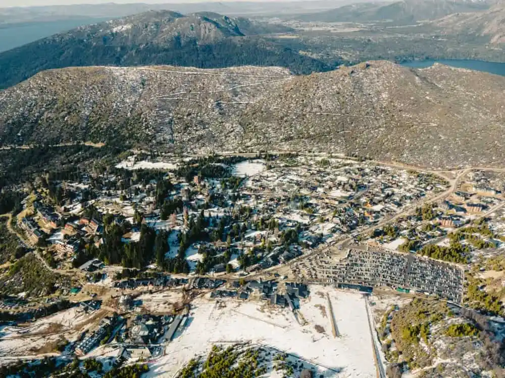 Vista aérea de una zona de montaña de Bariloche con nieve, viviendas y lagos entre los cerros