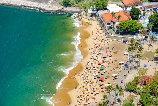 Vista aérea de una playa de Brasil con turistas, mar verde y palmeras junto a la costa