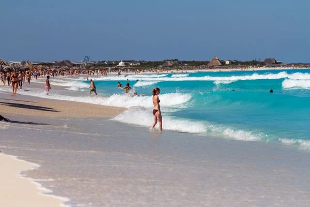 Vacaciones en el Caribe en verano 2027: costos desde Argentina Playa del Caribe con arena clara, mar turquesa y turistas durante el verano