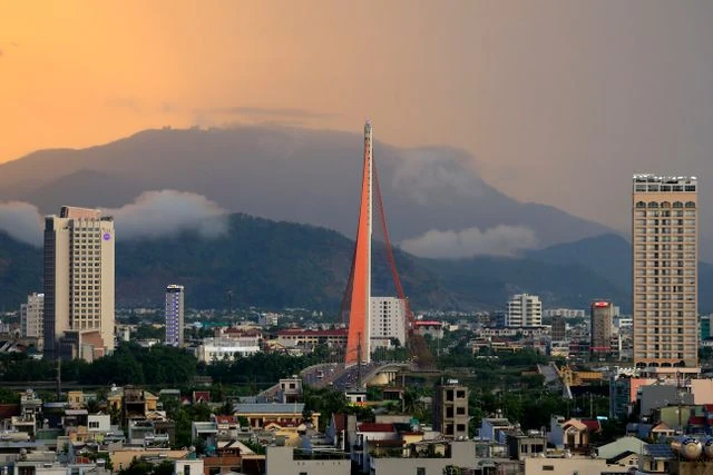 Da Nang, Vietnam: destino en crecimiento para viajar en 2027 Vista urbana de Da Nang, Vietnam, con puente moderno y montañas cubiertas de nubes al fondo