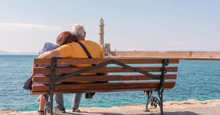 Pareja mayor sentada frente al mar durante una jornada tranquila junto a la costa