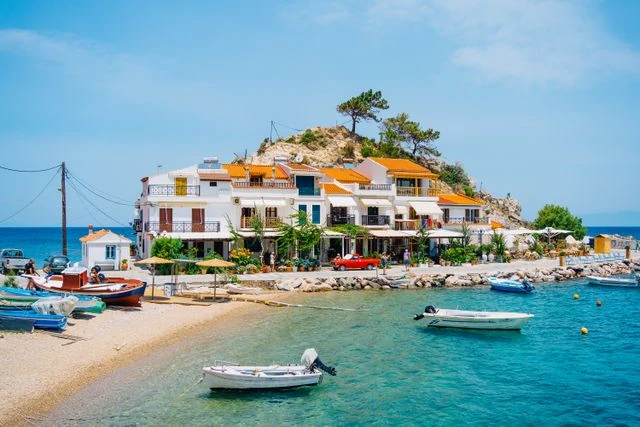 Samos, Grecia: isla del mar Egeo para viajar en 2027 Pueblo costero de Samos, Grecia, con casas blancas, pequeñas embarcaciones y aguas turquesas del mar Egeo